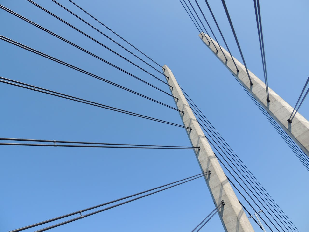 A modern suspension bridge with steel cables set against a clear blue sky, showcasing architectural elegance.